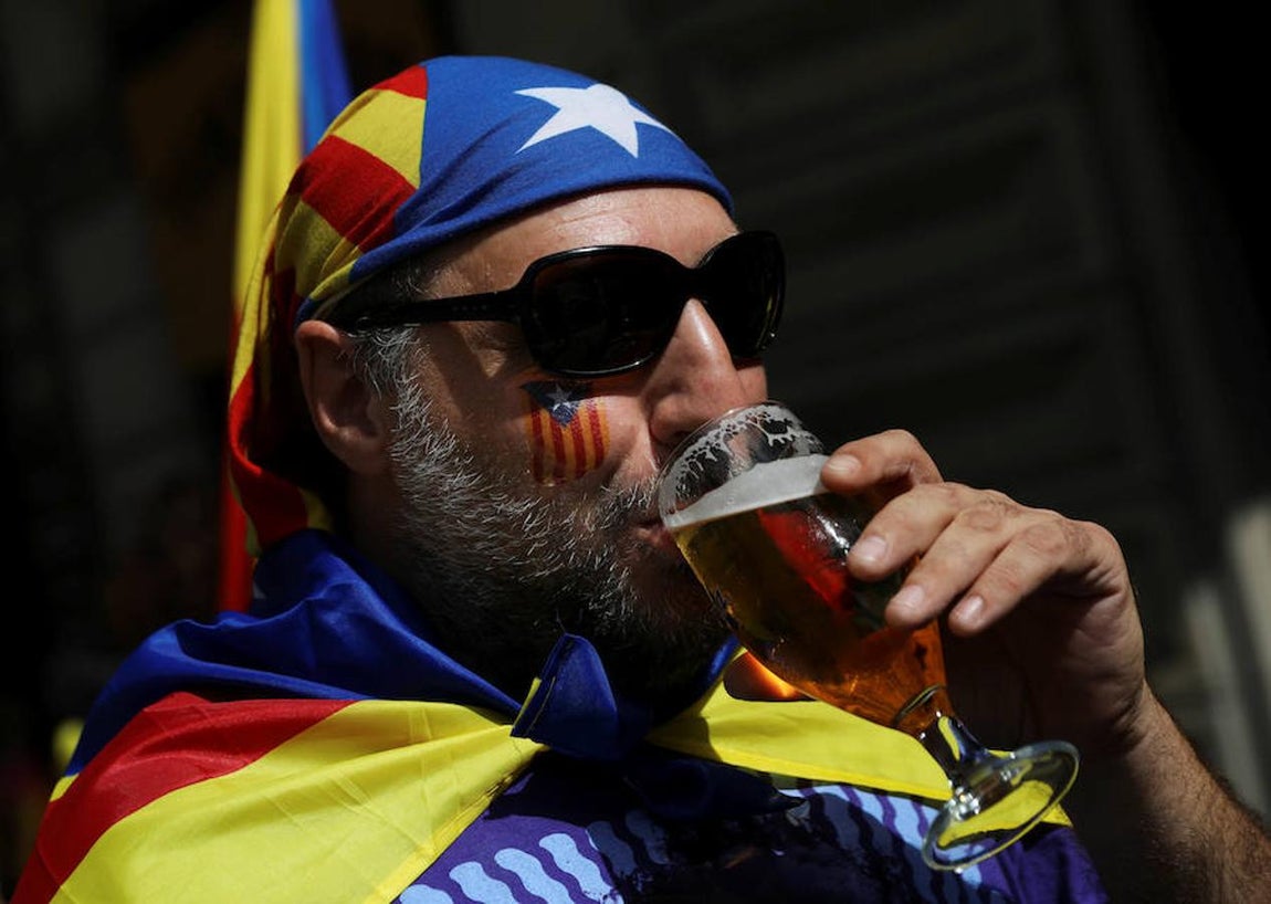 Hombre bebiendo cerveza con la «estelada» en cabeza, cara y espalda. 