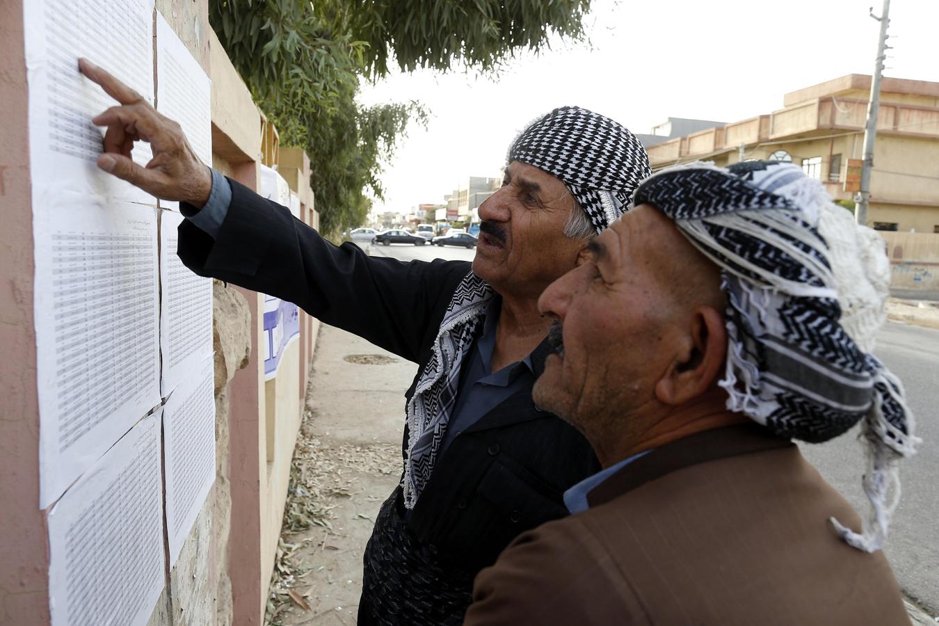 Kurdos buscan sus nombres en las lista de censo antes de votar. 