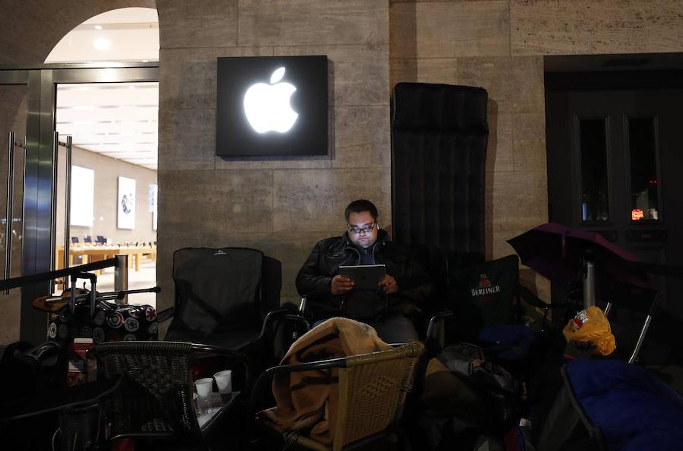 Un cliente mira su dispositivo móvil mientras acampa frente a una tienda Apple en Berlín, Alemania. 