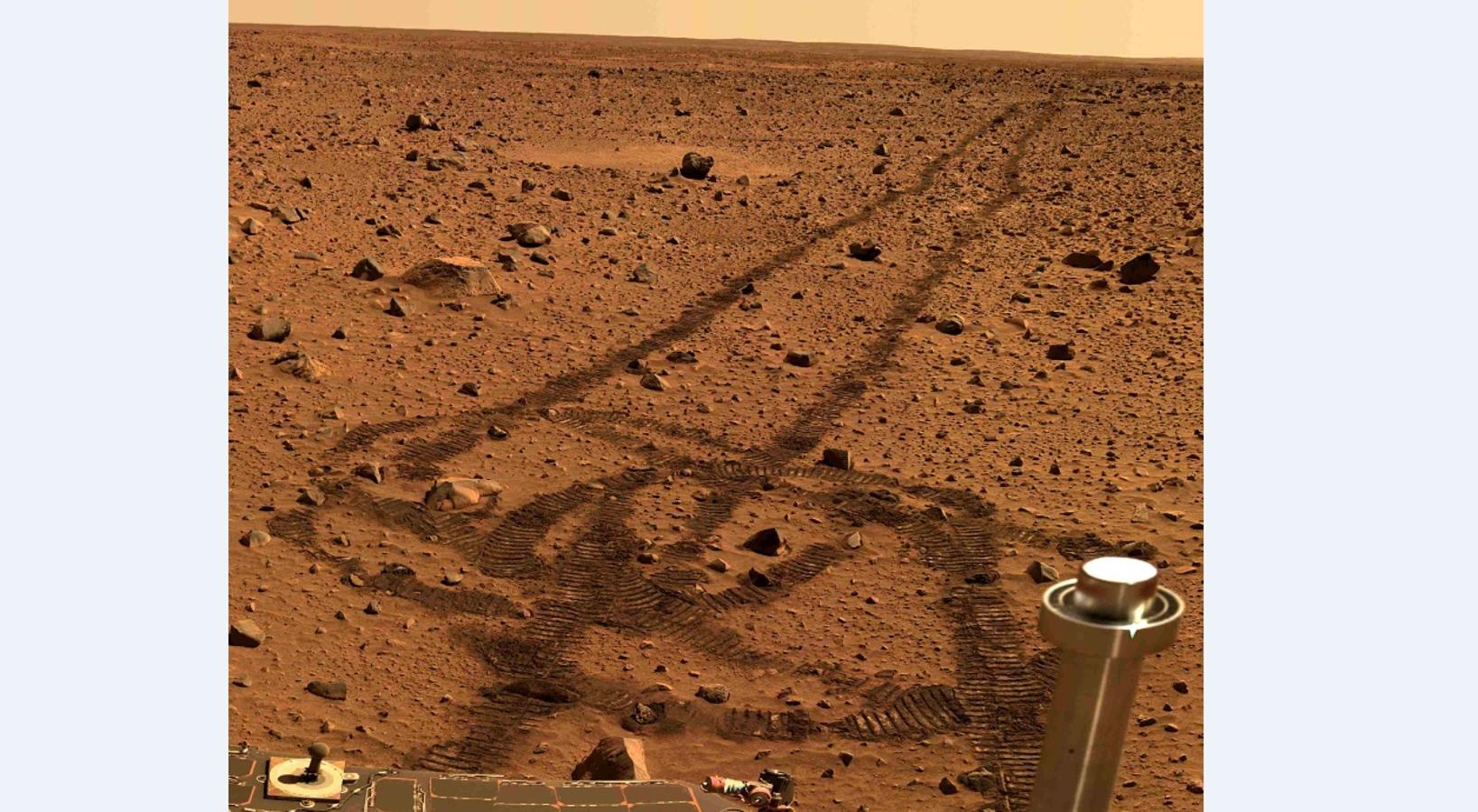 Huellas de un rover de la NASA en el suelo rojizo de Marte. 