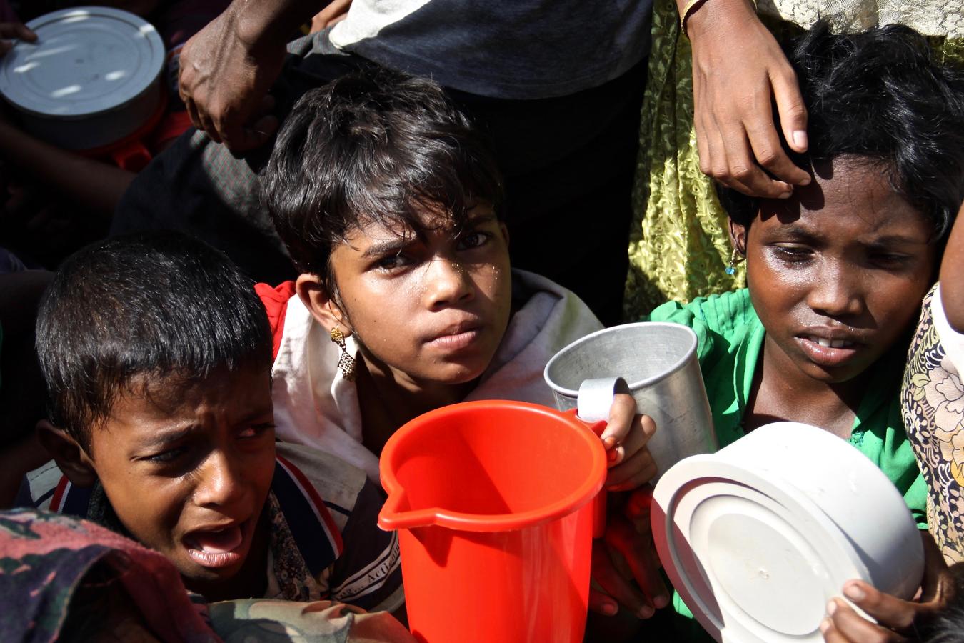 Entre lágrimas, un grupo de niños rohingyas esperan bajo el sol el reparto de comida en el campamento de refugiados de Moinnerghona. 