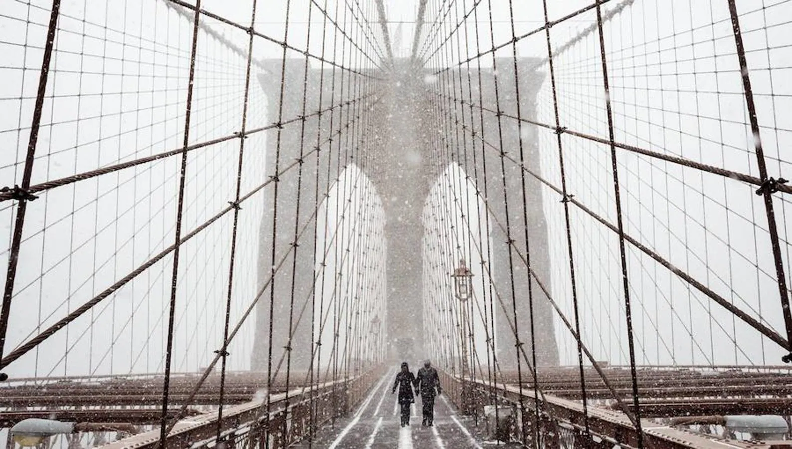 Peatones se protegen de la nieve y del viento mientras cruzan el puente de Brooklyn.. 