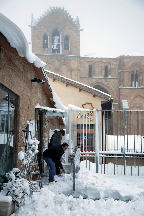 Dos hombres retiran la nieve del acceso a su establecimiento junto a la basílica de San Vicente de Ávila. 