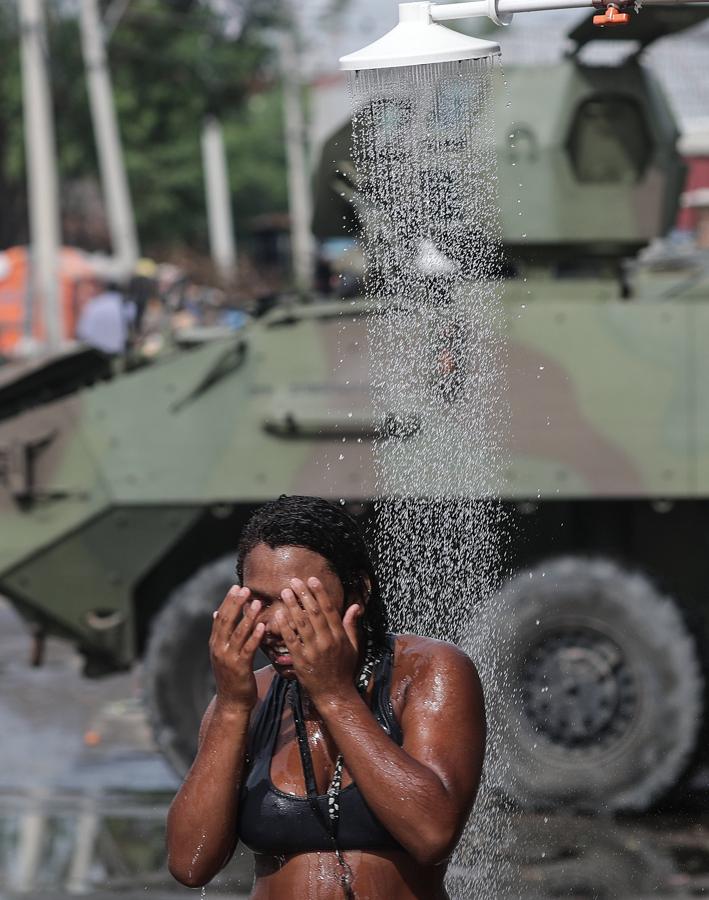 Una mujer se ducha frente a uno de los tanques del ejército. 