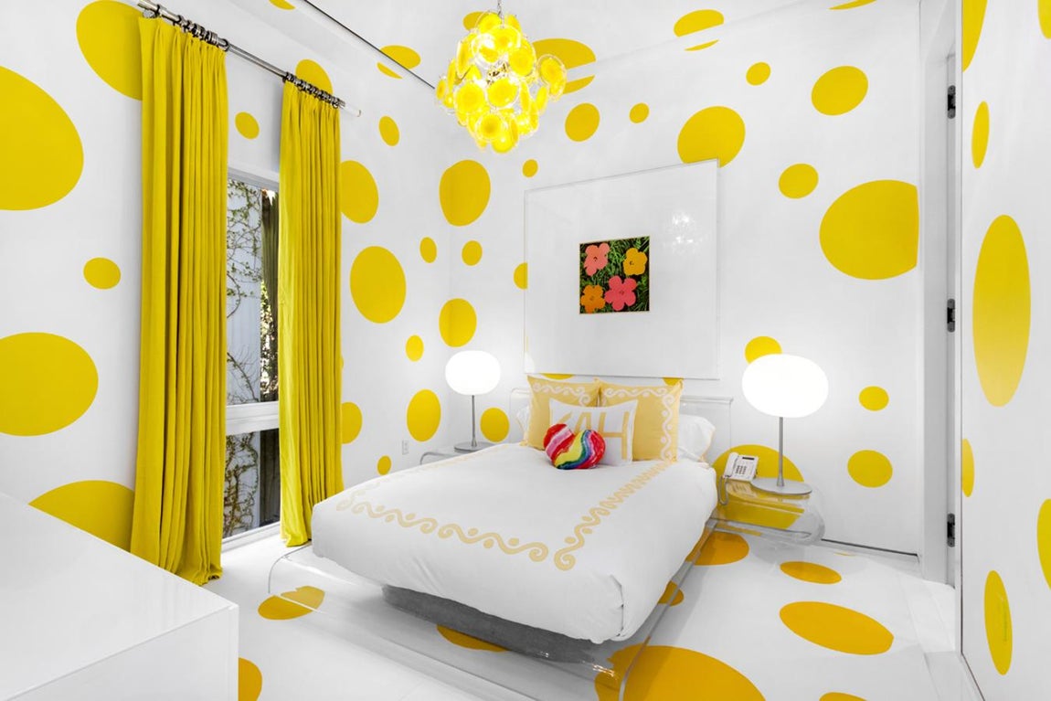 Dormitorio amarillo. Todo en la habitación se pliega a la obra que pende sobre el cabecero: «Flores», de Andy Warhol. Los puntos sobre la pared prentenden enfatizar el efecto de la pintura, la composición de la pared nació de la creatividad de Martyn Lawrence Bullard, la pintó Benjamin Moore
