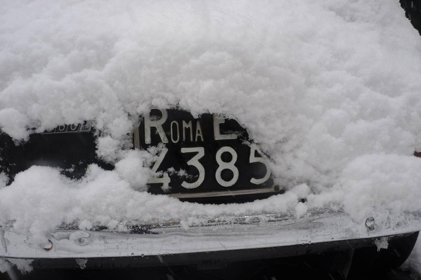 La nieve casi cubre por completo la matrícula de un coche durante una intensa nevada en Roma. 