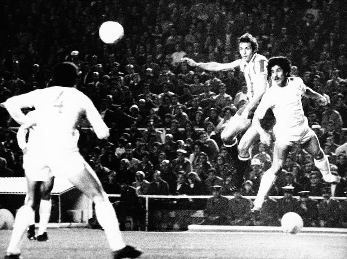 Quini trata de cabecear un balón junto al madridista Benito en un partido. 