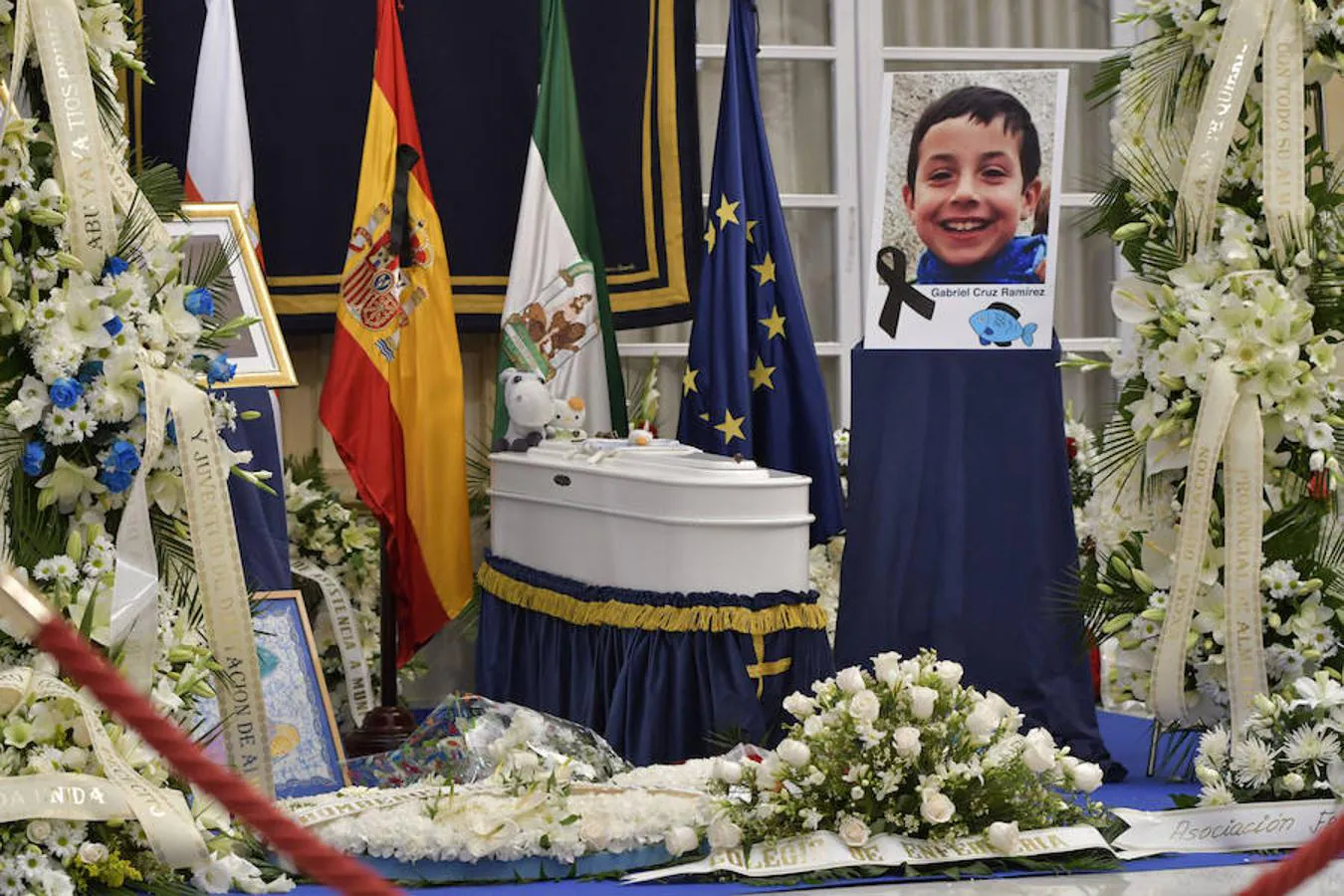 Ramos de flores junto al féretro y una fotografía en la capilla ardiente del niño Gabriel Cruz instalada esta tarde en el Palacio Provincial de la Diputación de Almería.. 