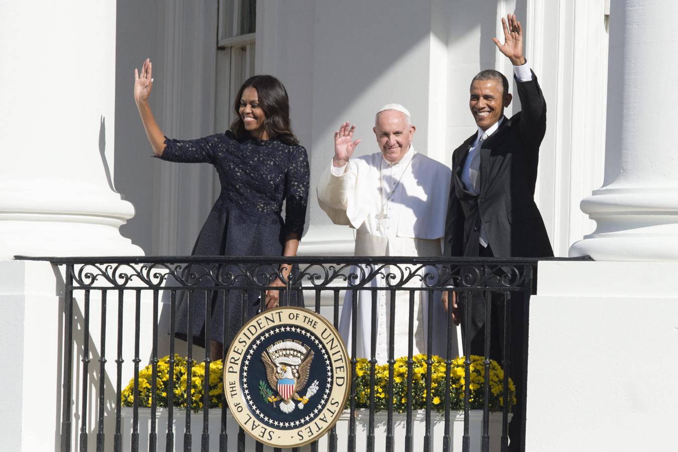 Francisco, el presidente de Estados Unidos, Barack Obama (dcha), y la primera dama Michelle Obama, saludan desde un balcón de la Casa Blanca, Washington, EE.UU., el 23 de septiembre del 2015. 