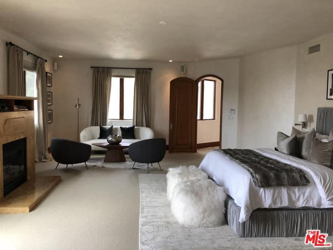 Eva Longoria. Duerme frente a la chimenea en un dormitorio con salida al jardín. Los tonos clásicos de la habitación contrastan con los elementos que rodean la cama: alfombra brillante, puff peludo y abundantes mantas y somier plisado