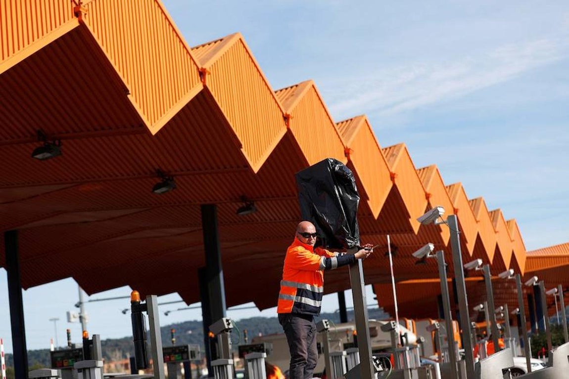 Operarios de autopistas trabajan en quitar las bolsas en las cámaras del peaje de la autopista AP-7. 