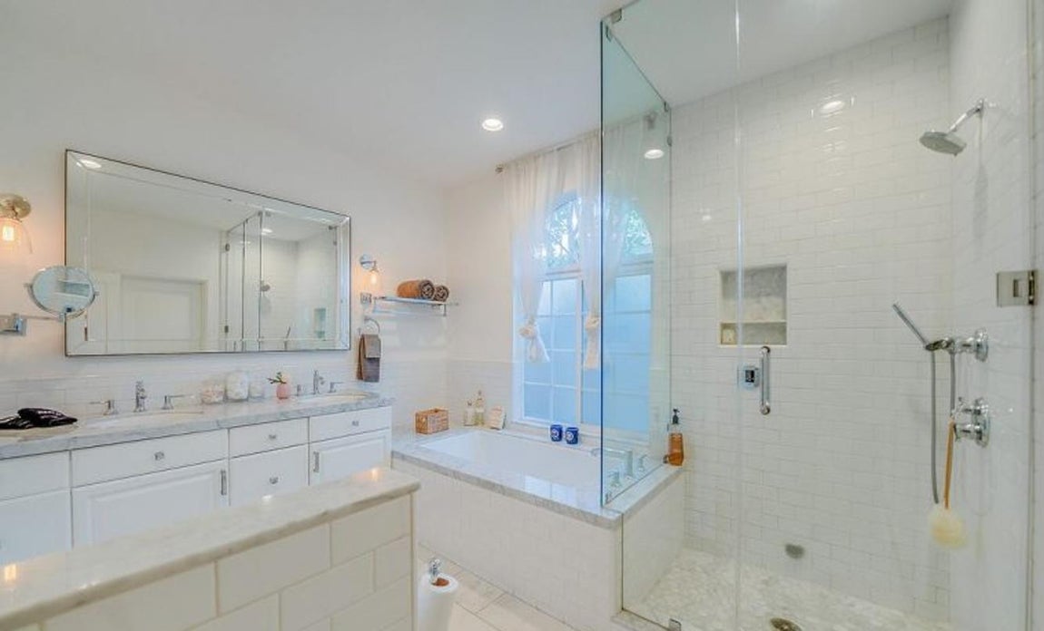 Baño tipo spa. La casa tiene cuatro baños en total, pero el principal de ellos tiene una gran bañera cuadrada de corte minimalista, zona de vapor y mobiliario en blanco, es perfecto para desconectar