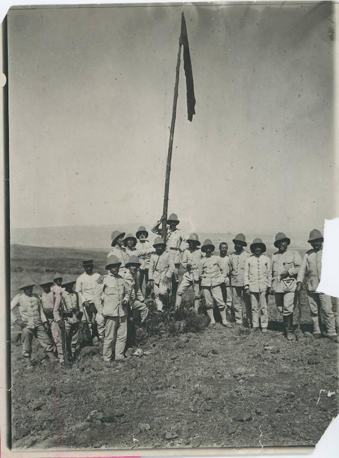 Guerra de Marruecos, el coronel Primo de Rivera con jefes y oficiales del regimiento de Melilla junto a la bandera izada en el Gurugú.. Miguel Prmo de Rivera se sitúa abrazando el mástil