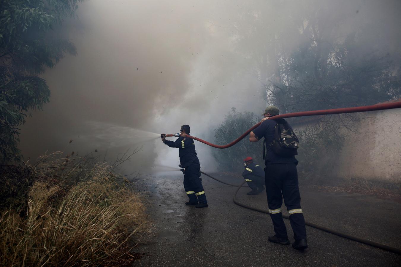 Bomberos tratan de extinguir un incendio en Neo Voutsa, al noreste de Atenas (Grecia). 