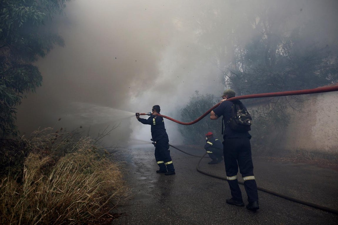 Bomberos tratan de extinguir un incendio en Neo Voutsa, al noreste de Atenas (Grecia). 