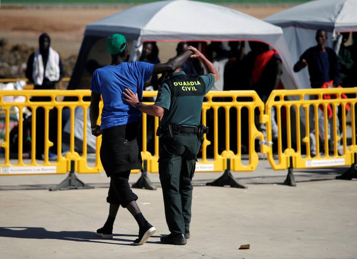 Uno de los guardias civiles –que cuida y vigila a las personas que llegan en patera a las costas de Cádiz y son trasladadas al pabellón «Antonio Gavira», en el municipio Los Barrios, cerca de Algeciras– aparta el brazo del inmigrante que se abrazaba a su cuello.. 