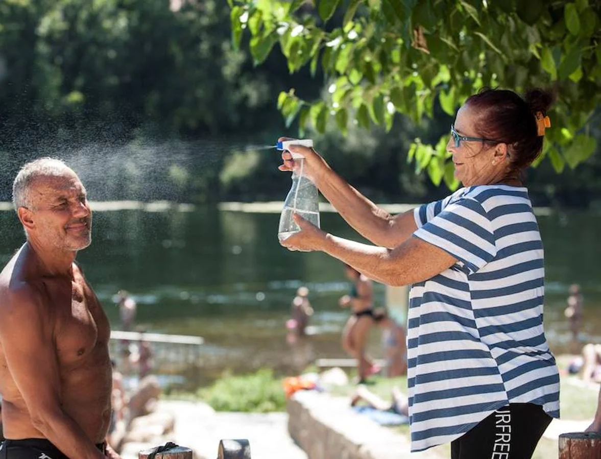 España también sufre las consecuencias del calor. Una mujer refresca a un hombre en la zona fluvial del río Miño y las termas de A Chavasqueira, en Galicia. La AEMET prevé una subida de temperatura notable en Orense, donde se pueden llegar a alcanzar los 40 grados