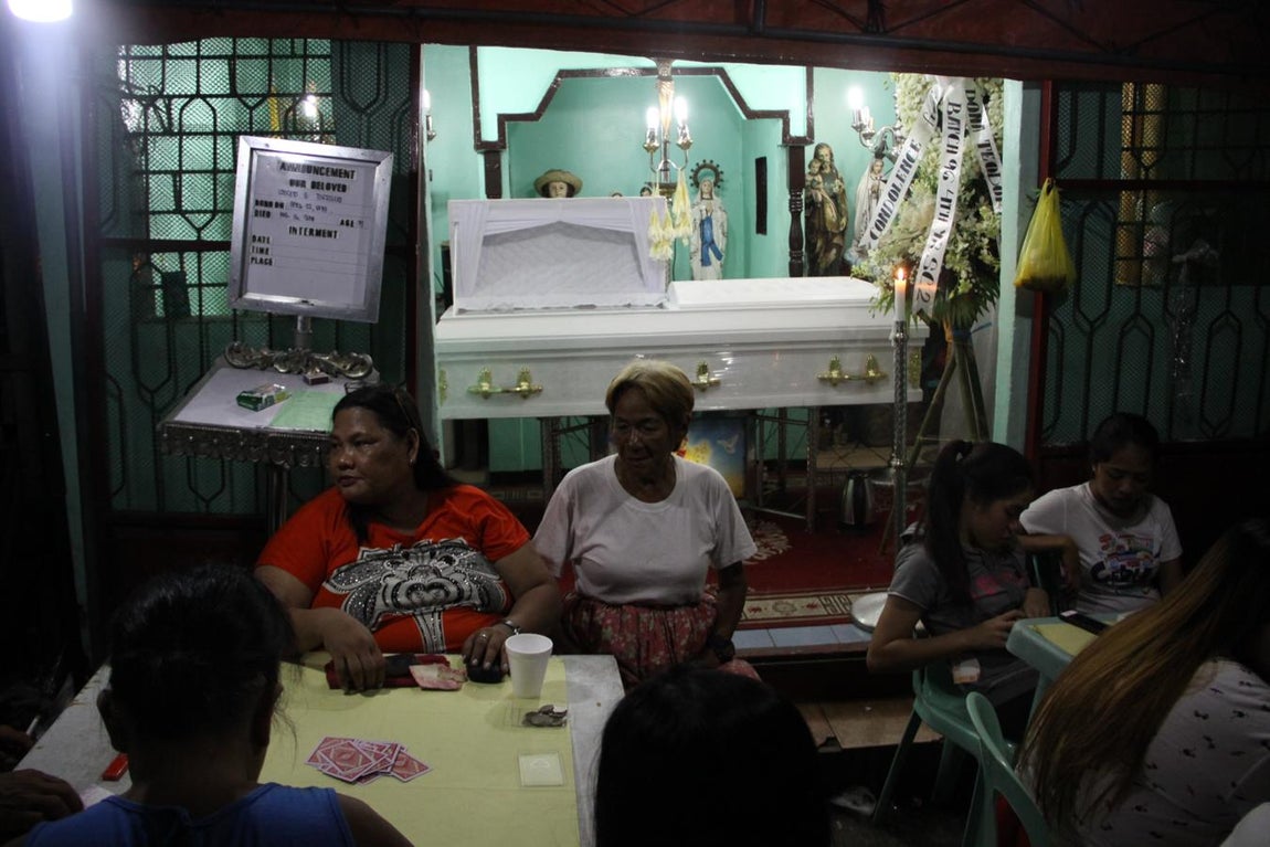 Como manda la tradición, los amigos de Lousieto Torrillia acuden a su velatorio en plena calle, donde comen y beben para despedirlo con una fiesta y juegan a las cartas para recaudar fondos con los que pagar los 30.000 pesos (500 euros) que cuesta su funeral. 