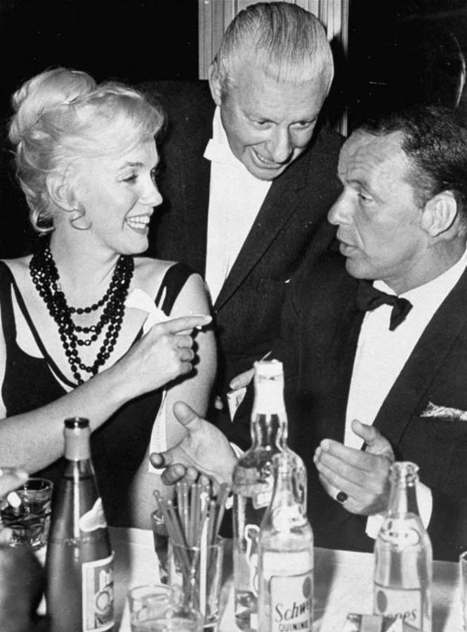 Marilyn Monroe charla con Frank Sinatra durante una cena. 