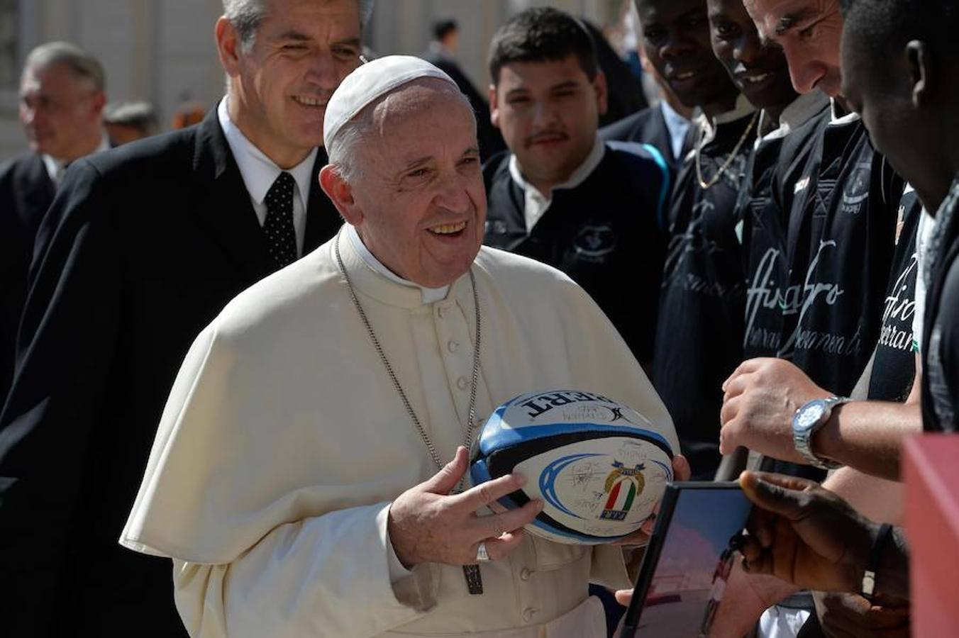 El papa Francisco recibe una pelota de rugby firmada por los miembros de un equipo formado por refugiados tras su audiencia general en la Plaza de San Pedro del Vaticano