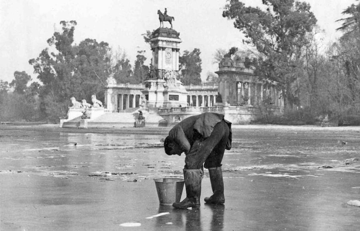 20.. 13 de enero de 1954. Pescando en las heladas aguas del estanque. Empleados del Ayuntamiento rescatan los peces para trasladarlos a aguas mas templadas. La baja temperatura heló la poca agua del estanque del Retiro