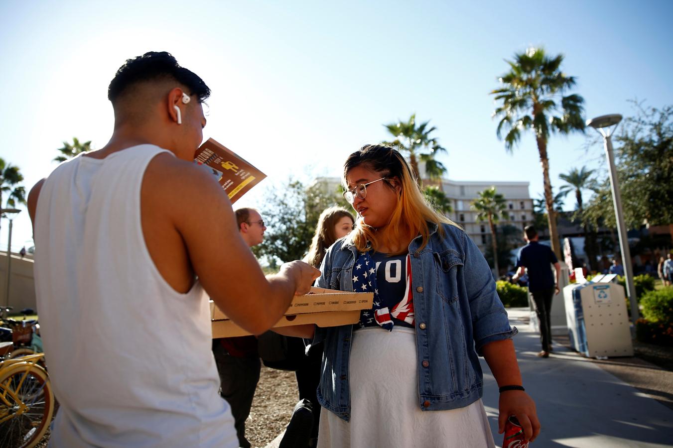 Las elecciones legislativas de EE.UU., en imágenes. Kathryn Quintin, de Jóvenes Invencibles, a la derecha, ofrece pizza gratis a los estudiantes que esperan en fila para votar en el colegio electoral ASU Palo Verde West durante las elecciones en Tempe (Arizona)