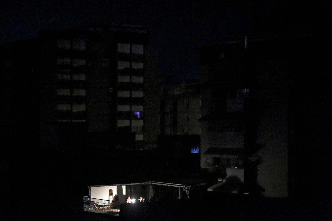 Un grupo de personas disfruta de la luz de una linterna en Caracas, en una nueva jornada de apagón. 