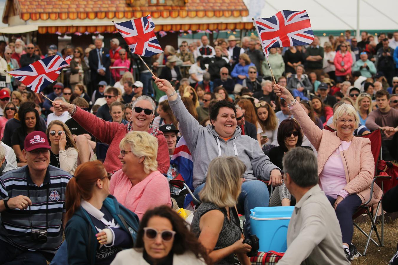 Los asistentes celebran con banderas de Reino Unido. 