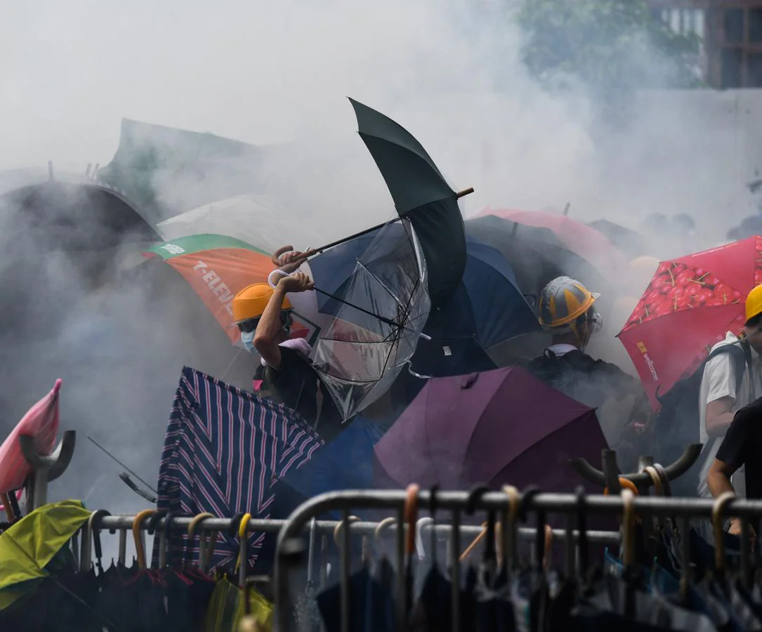 Un grupo de manifestantes responden golpeando con paraguas a los policías tras el lanzamiento de gas pimienta.. 