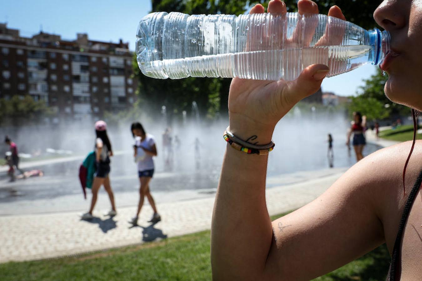 Una mujer bebe agua para refrescarse en las inmediaciones de los chorros de Madrid Río. 