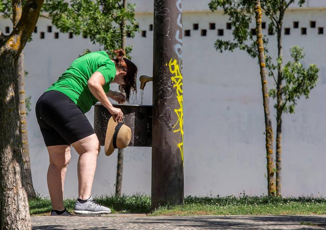 Una mujer se refresca en una fuente de Burgos a causa de las altas temperaturas registradas hoy en la ciudad. 