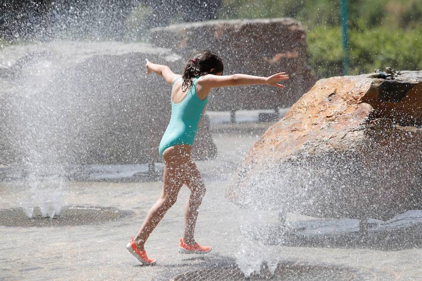 Una niña juega en una fuente de la Avenida José Atares, en Zaragoza. La ola de calor ha comenzado con máximas de 39ºC en la capital de Aragón. 