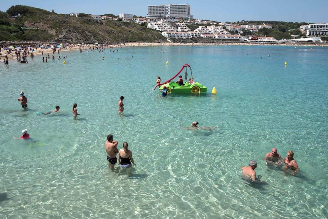 Decenas de personas disfrutan del sol en la playa de Arenal Díen Castell, en Menorca. A partir de mañana se pueden alcanzar los 34°C en la isla balear. 