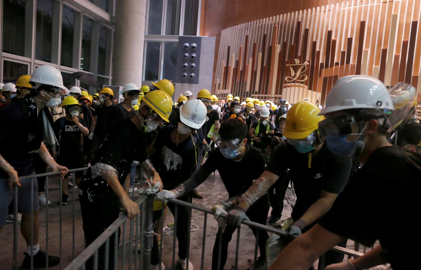 Los manifestantes utilizan barras de metal para romper las puertas y ventanas de cristal de la sede del gobierno en Hong Kong. 