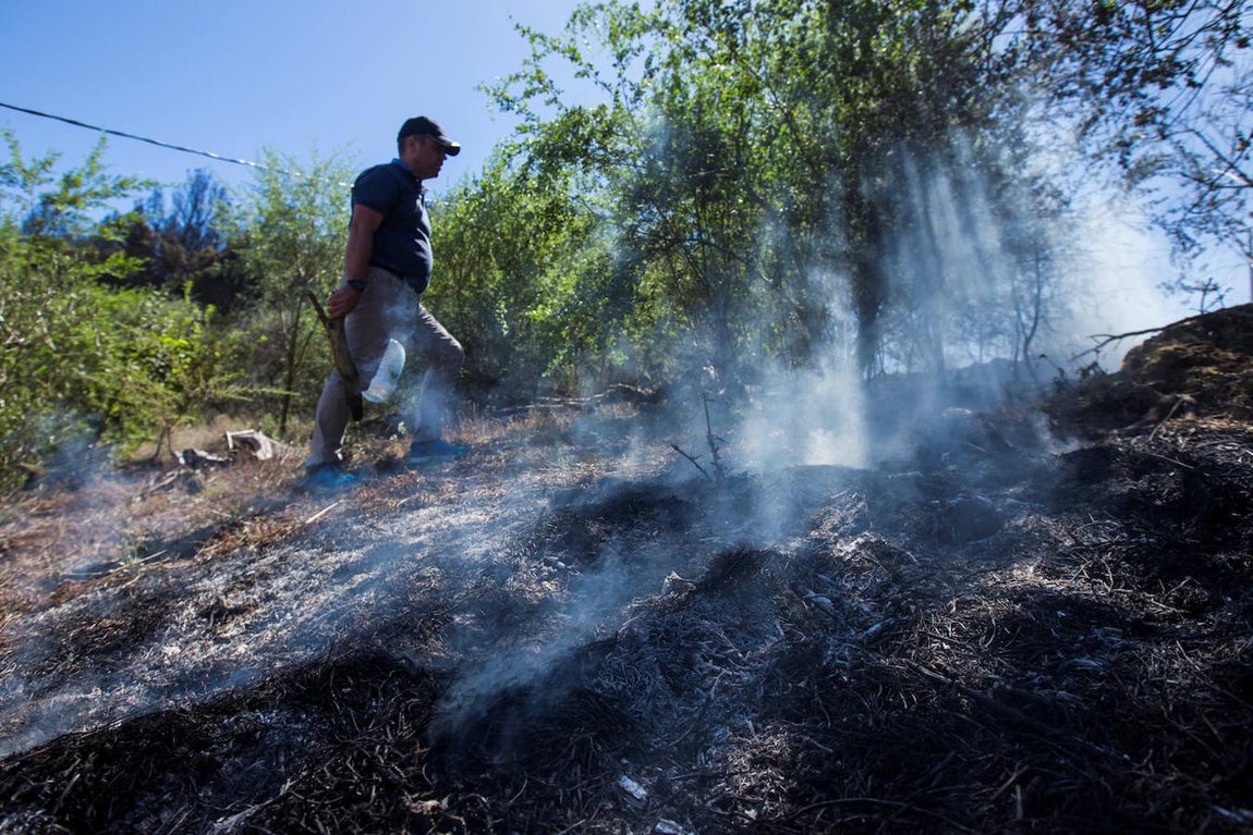 Un hombre inspecciona un área quemada después del incendio. 