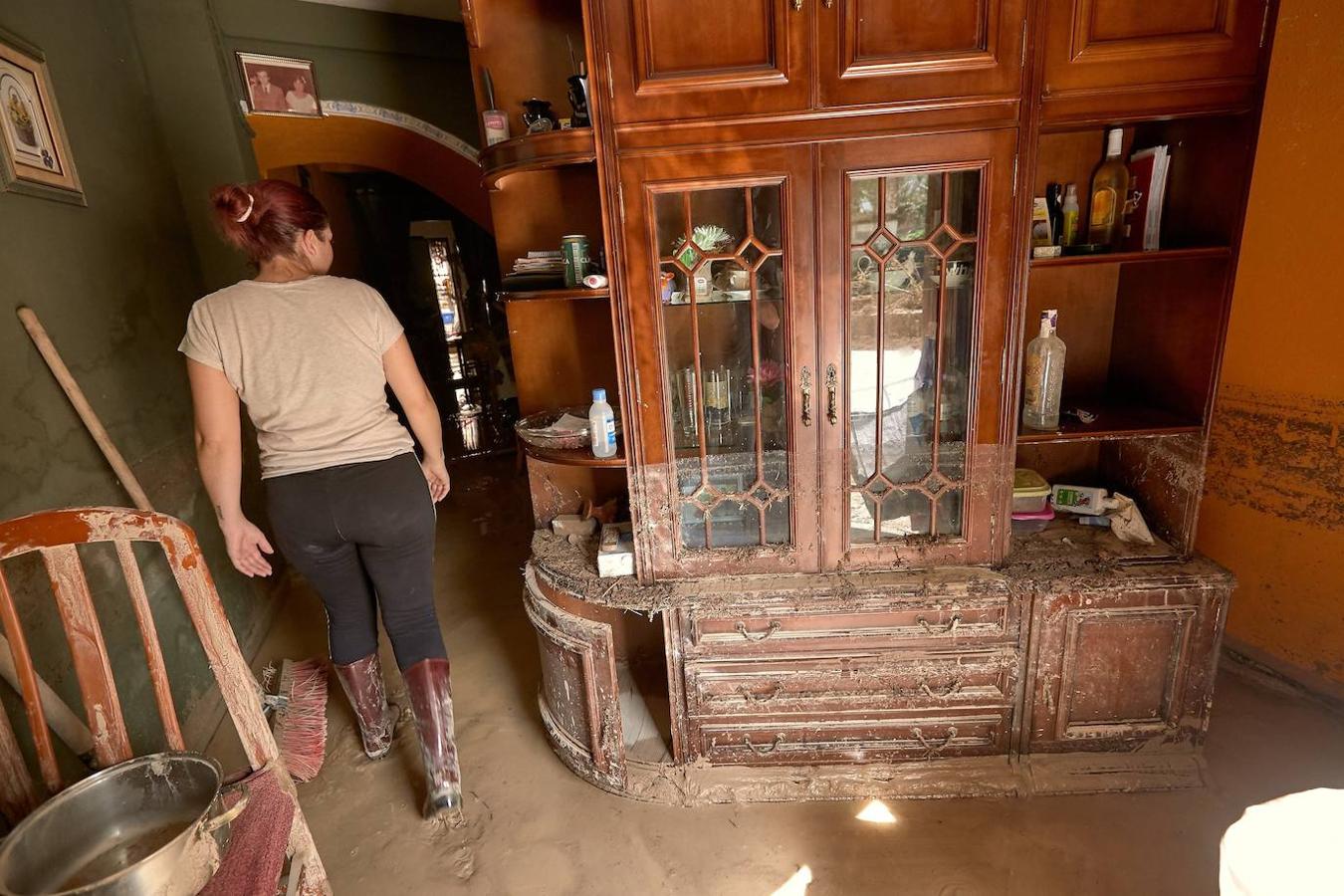 Una mujer enseña su casa este viernes destrozadas por el desbordamiento del río Clariano a su paso por la localidad valencia de Ontinyent. 