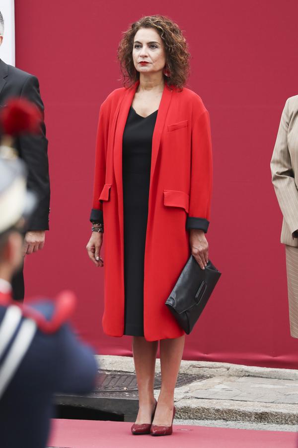 La ministra María Jesús Montero ha optado por un vestido negro, que ha combinado con un abrigo rojo y una cartera de mano a juego con el vestido. 