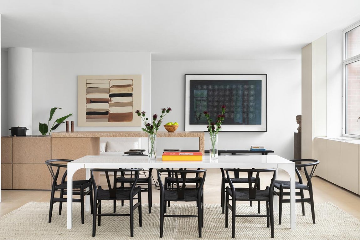 El loft minimalista de Kim Kardashian. Sus techos de 3 metros de altura aportan una mayor sensación de amplitud y en la zona de comedor su gran alfombra de fibras naturales delimita el espacio sobre el que se ubica una gran mesa blanca con ocho sillas negras a su alrededor.