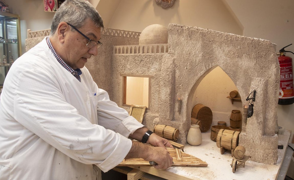 Manos a la obra. Uno de los belenistas de la Asociación trabaja envejeciendo la puerta de una bodega del belén.
