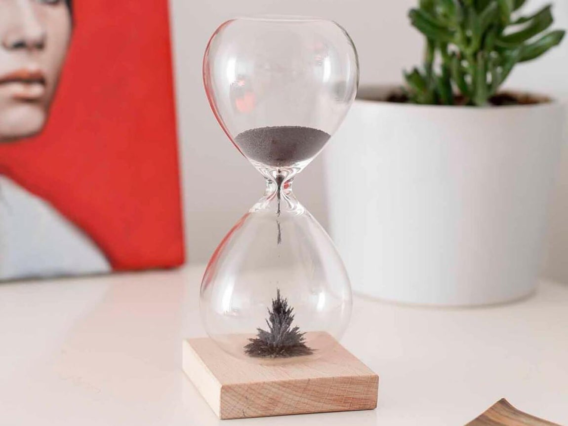 Reloj de cristal con arena magnética. Reloj de arena magnética, con soporte de madera. Duración de 1 minuto. Sus medidas son: 16,5 x 7 x 7 cm. Está disponible por 19,95 euros en El regalador.