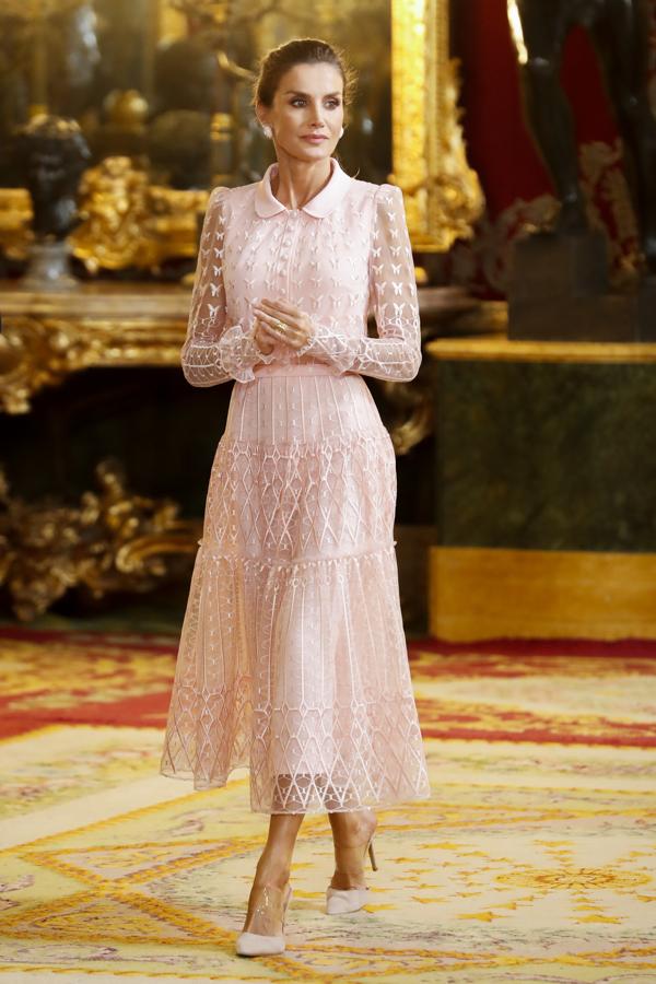 La Reina Letizia lució en la Fiesta Nacional uno de sus vestidos más románticos del año: de plumeti midi en color rosa con corte en la cintura, cuello de estilo «baby doll» y mangas transparentes. Un diseño con mariposas bordadas que destacaba también por la abotonadura delantera y la falda fluida de varias capas.. 