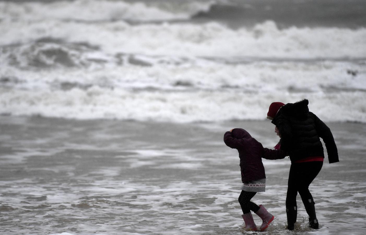 Una madre y su hija en la orilla del mar, revuelto por las olas y el viento huracanado en en Bournemouth