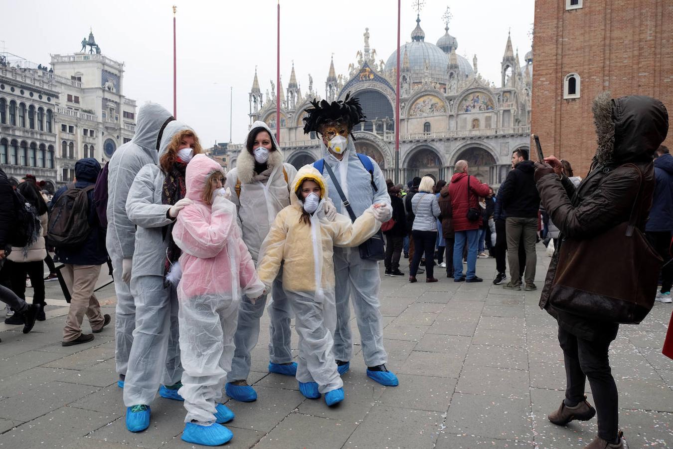 Una familia, en la que todos los miembros llevan trajes protectores, se toma una fotografía en Venecia. 