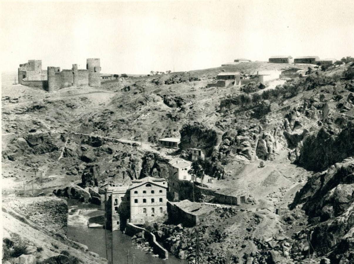 Obras para abrir una carretera sobre la presa del Artificio hacia 1930. Abajo, junto a la fábrica de harinas (1864), el edificio de la central eléctrica añadida en 1897. Foto Aldus. Archivo Municipal de Toledo. 