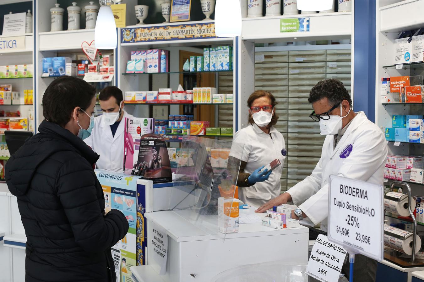 Empleados de una farmacia de la capital atienden protegidos a una mujer.. 