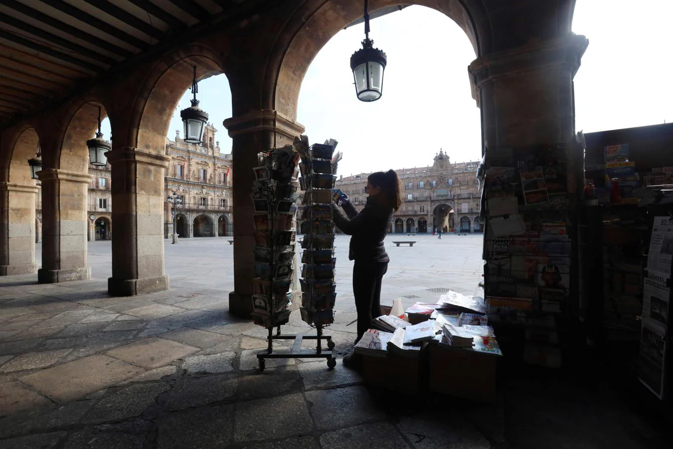 La Plaza Mayor, desierta. La responsable de una tienda de prensa coloca sus artículos en una Plaza Mayor salmantina desierta