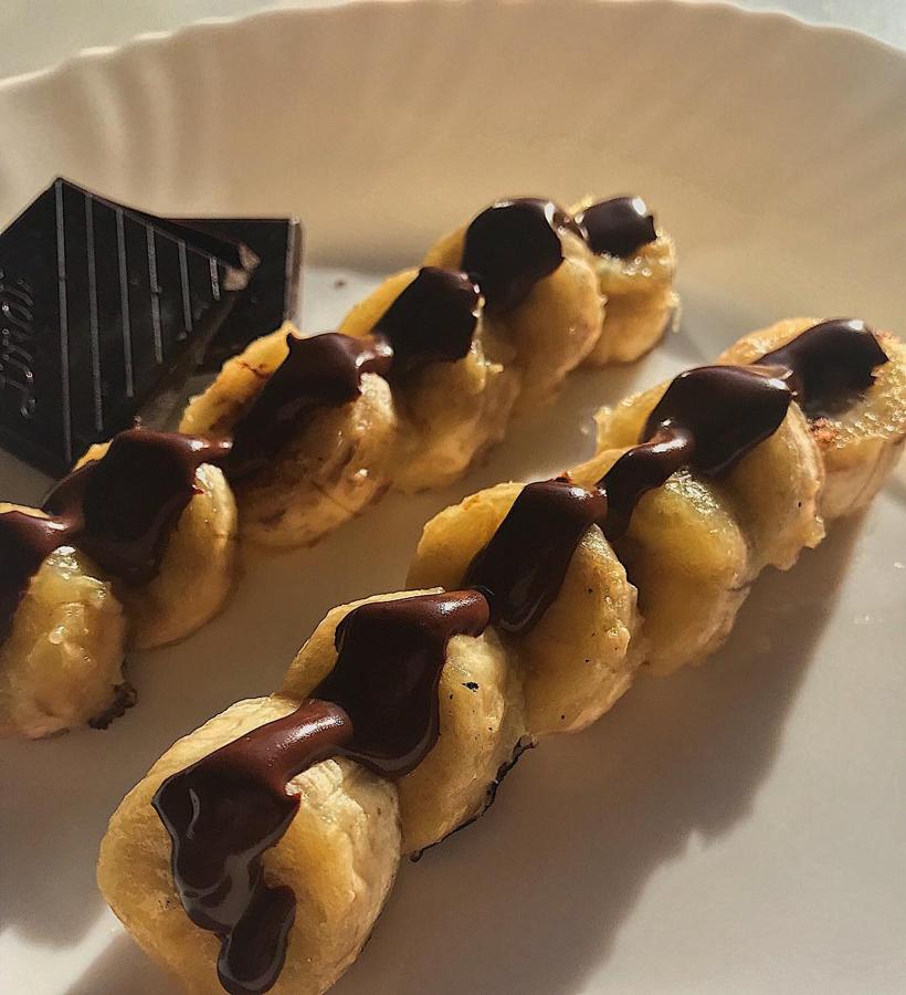 Plátano con chocolate puro. Para hacer este tentempié solo tendrás que pasar el plátano por la sartén (más o menos hasta que veas que se está derritiendo) y derretir chocolate (85% cacao) en el microondas para untarlo por encima. Si los metes unos minutos en el frigorífico o en el congelador el chocolate se solidificará y disfrutarás aún más del contraste de las texturas.