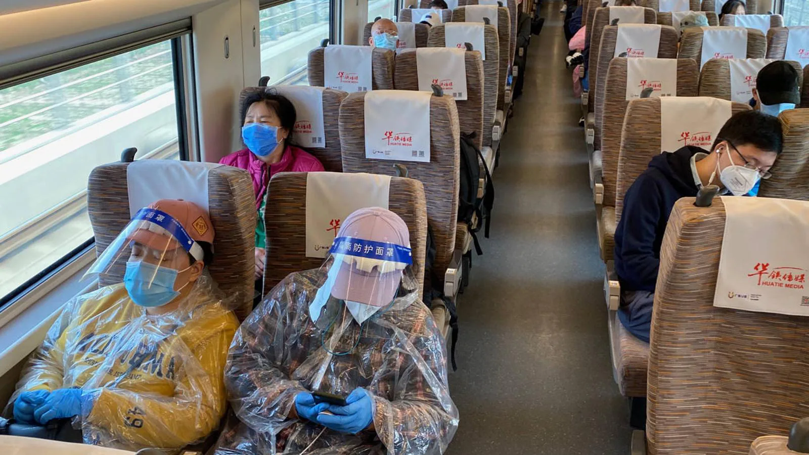 Además de mascarillas, gorras y guantes de látex, dos mujeres llevan viseras e impermeables de plástico para "blindarse" contra el coronavirus. 
