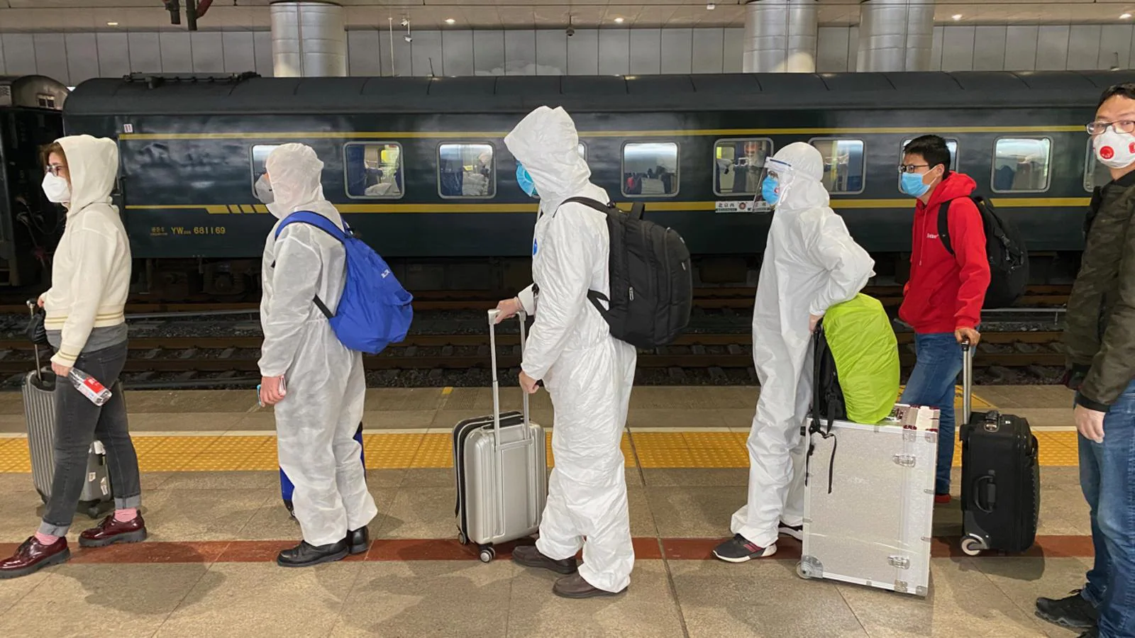 Pasajeros procedentes de Wuhan llegan a Pekín pertrechados con fantasmagóricos monos especiales de protección, la siniestra moda del mundo poscoronavirus. 