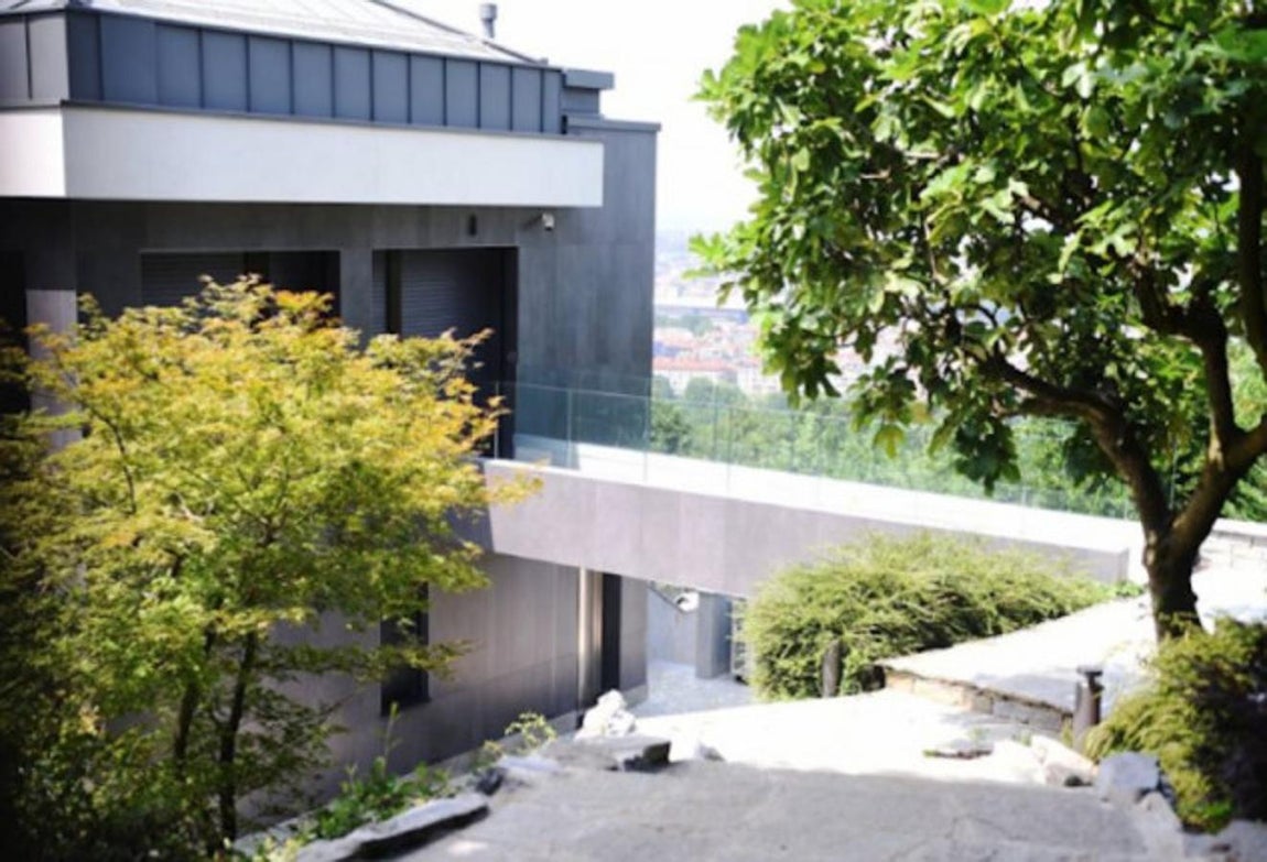 Dos villas unidas a través del jardín. La parcela en la que se encuentra la casa supera los 3.000 metros cuadrados mientras que la edificación ronda los 800 metros repartidos en tres plantas bajo una estética minimalista y aunque una parte de la vía se encuentra abierta al público, la posición estratégica de la casa, en lo alto de una colina, impide que sea visto.